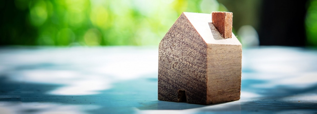 Een houten huisje op een tafel met een achtergrond van bomen en groene bladeren