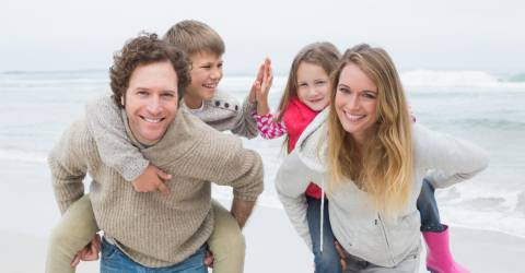 Gezin op het strand ouders met kinderen op hun rug
