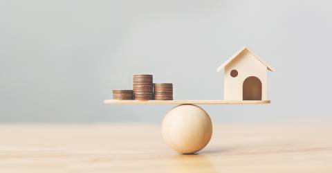 Houten huis en geld munten op hout schaal. Investeringen huis hypotheek